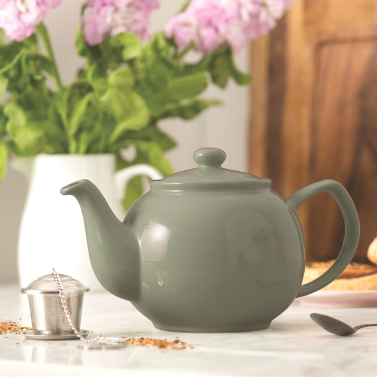 Sage green teapot with flowers in background
