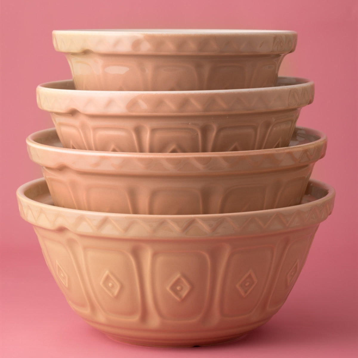 Stack of terracotta-colored bowls with textured pattern on a pink background