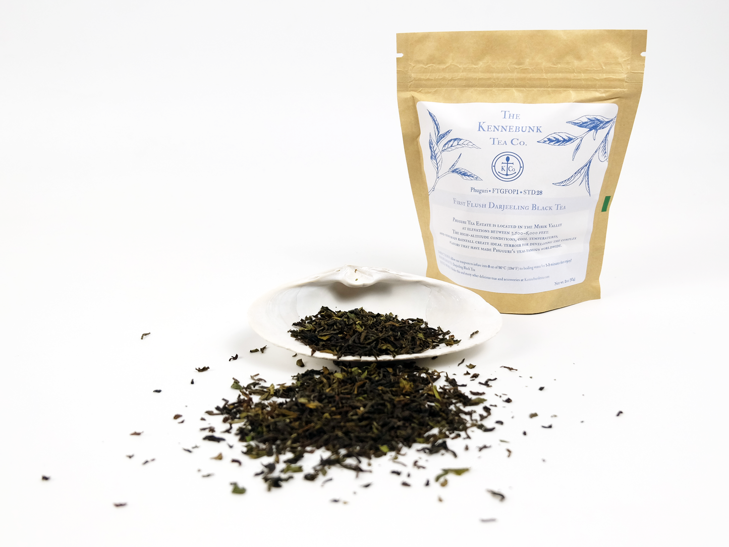 Phuguri first flush Darjeeling loose leaf tea on a white shell with 2oz kraft bag of tea behind
