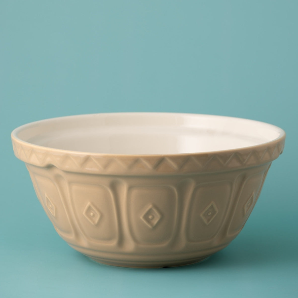 Beige ceramic bowl with diamond pattern on a teal background
