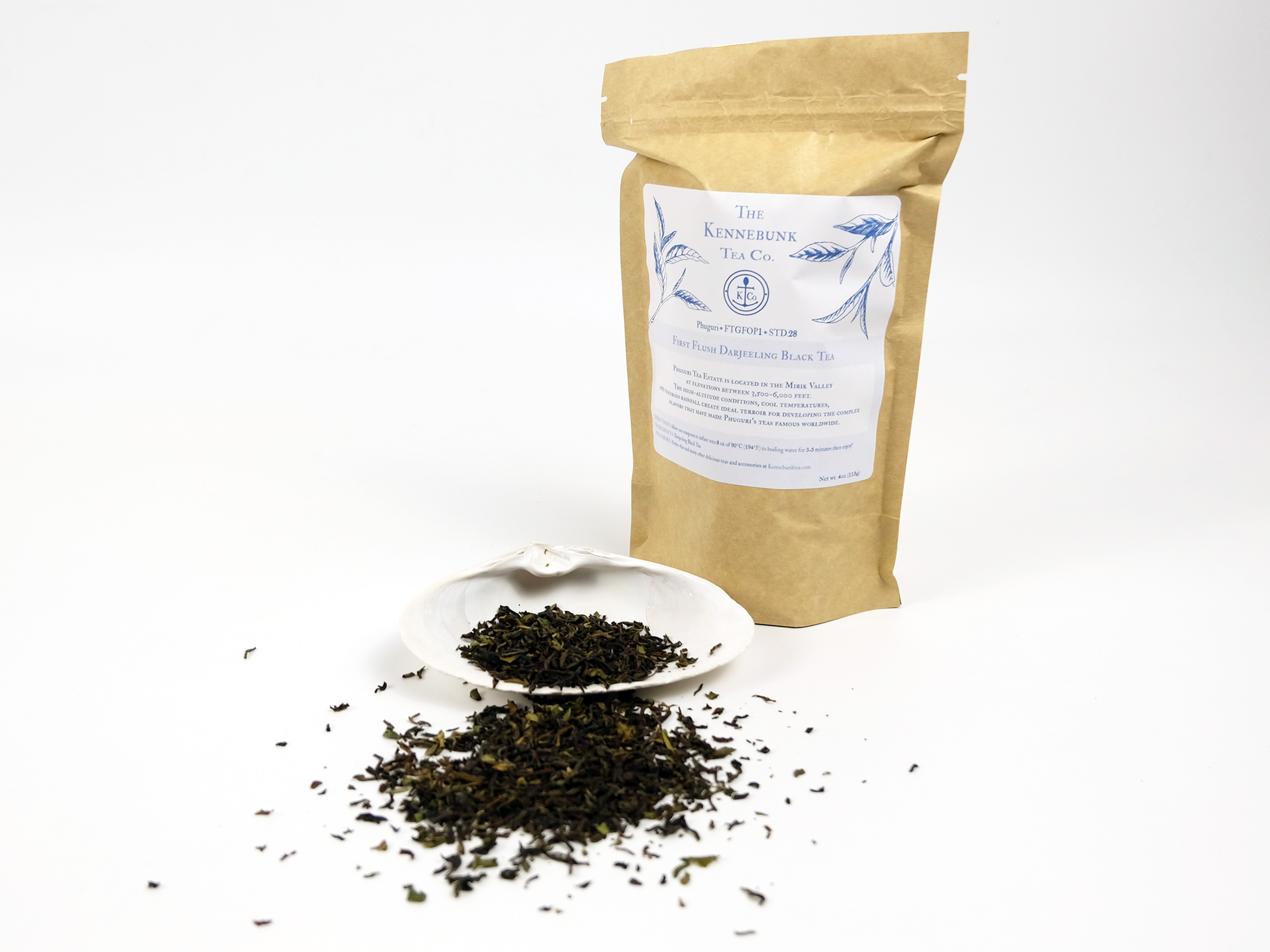 Phuguri first flush Darjeeling loose leaf tea on a white shell with 4oz kraft bag of tea behind