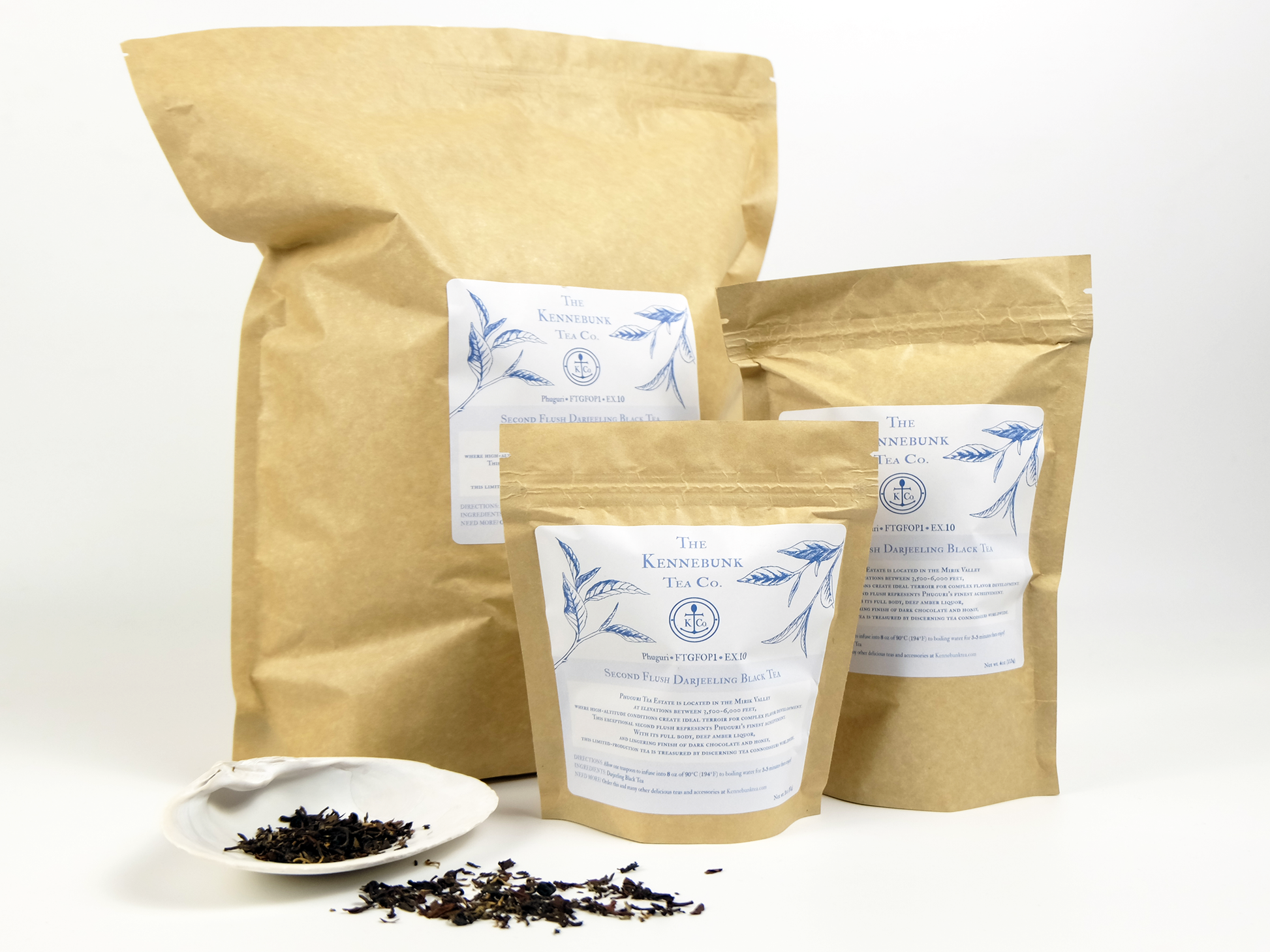 Phuguri second flush Darjeeling loose leaf tea on a white shell with three different-sized kraft tea bags behind