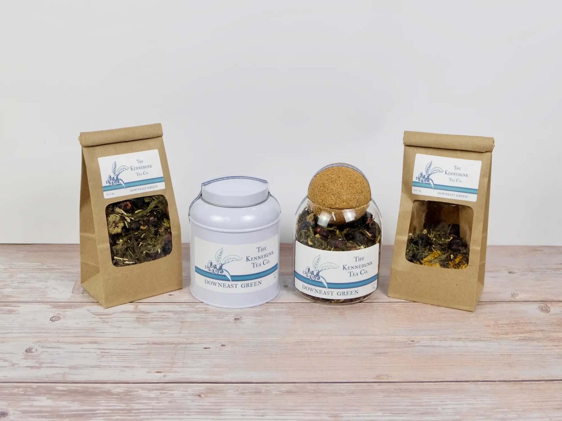 Downeast Green Tea loose leaf tea with two refill tea bags next to a tin and glass jar, all with Blueberry labels