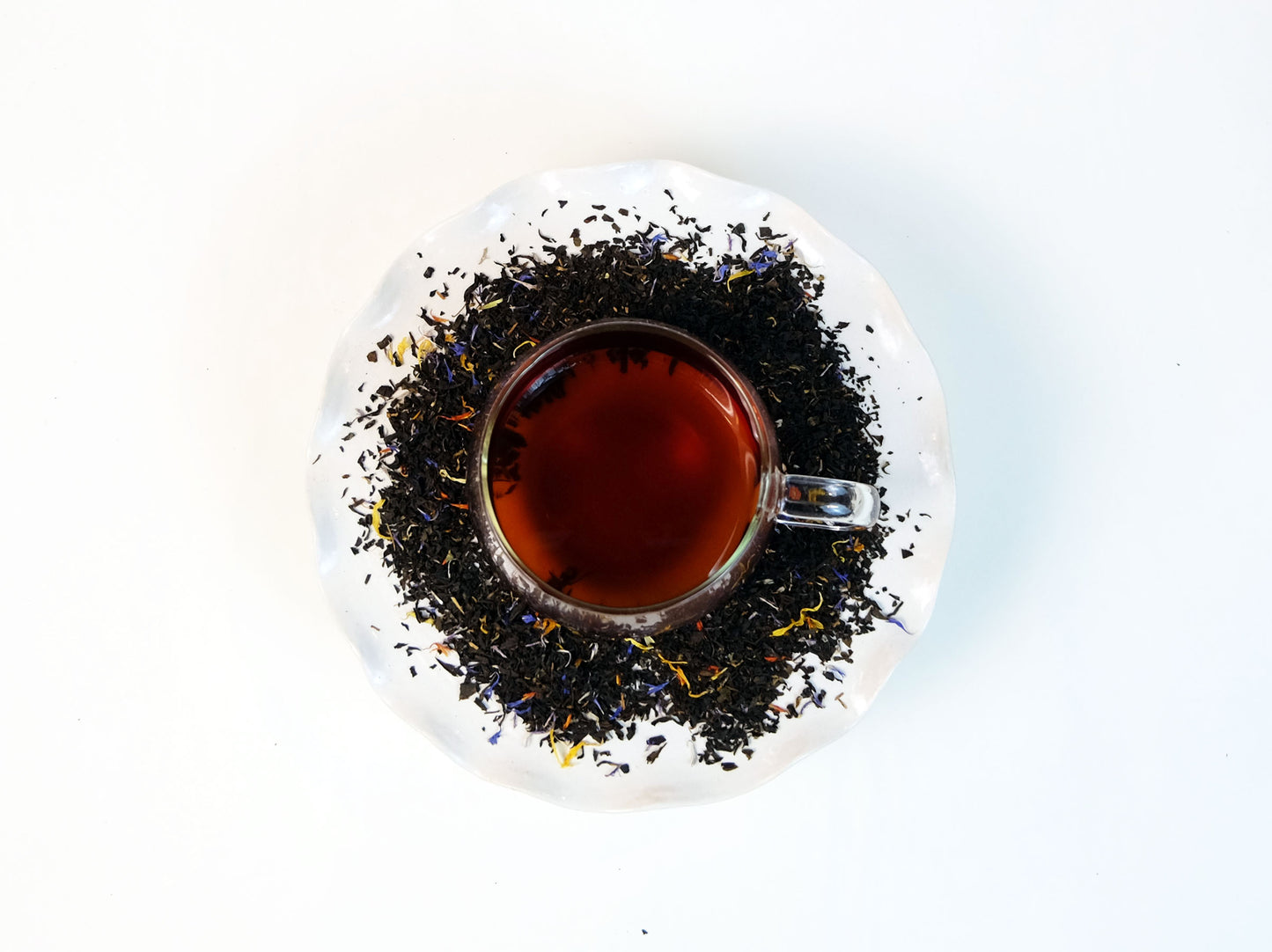 Katahdin Mountain Sunrise Tea brewed in a glass mug with loose leaf tea scattered around, top view