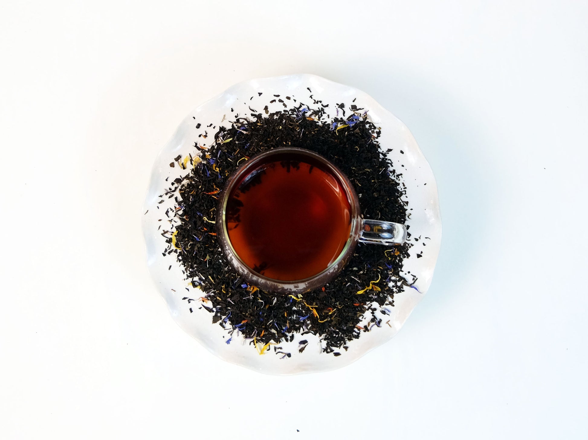 Katahdin Mountain Sunrise Tea brewed in a glass mug with loose leaf tea scattered around, top view