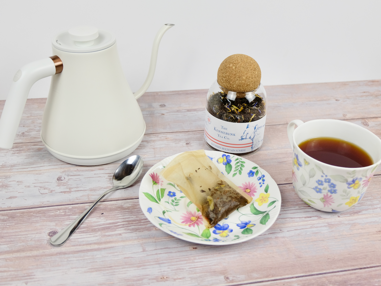 Katahdin Mountain Sunrise Tea brewed in a teacup with saucer and glass jar of tea with bear label