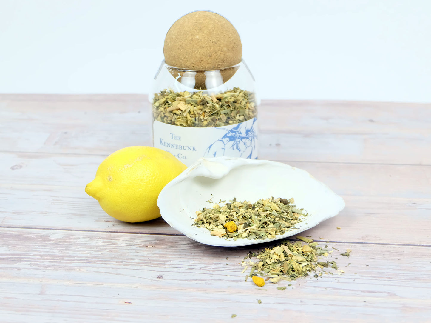 Lemon Ginger Tea loose leaf tea in a glass jar with a lemon and white shell beside it