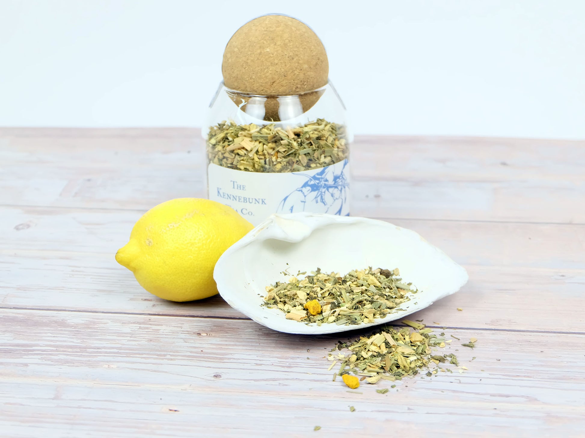 Lemon Ginger Tea loose leaf tea in a glass jar with a lemon and white shell beside it