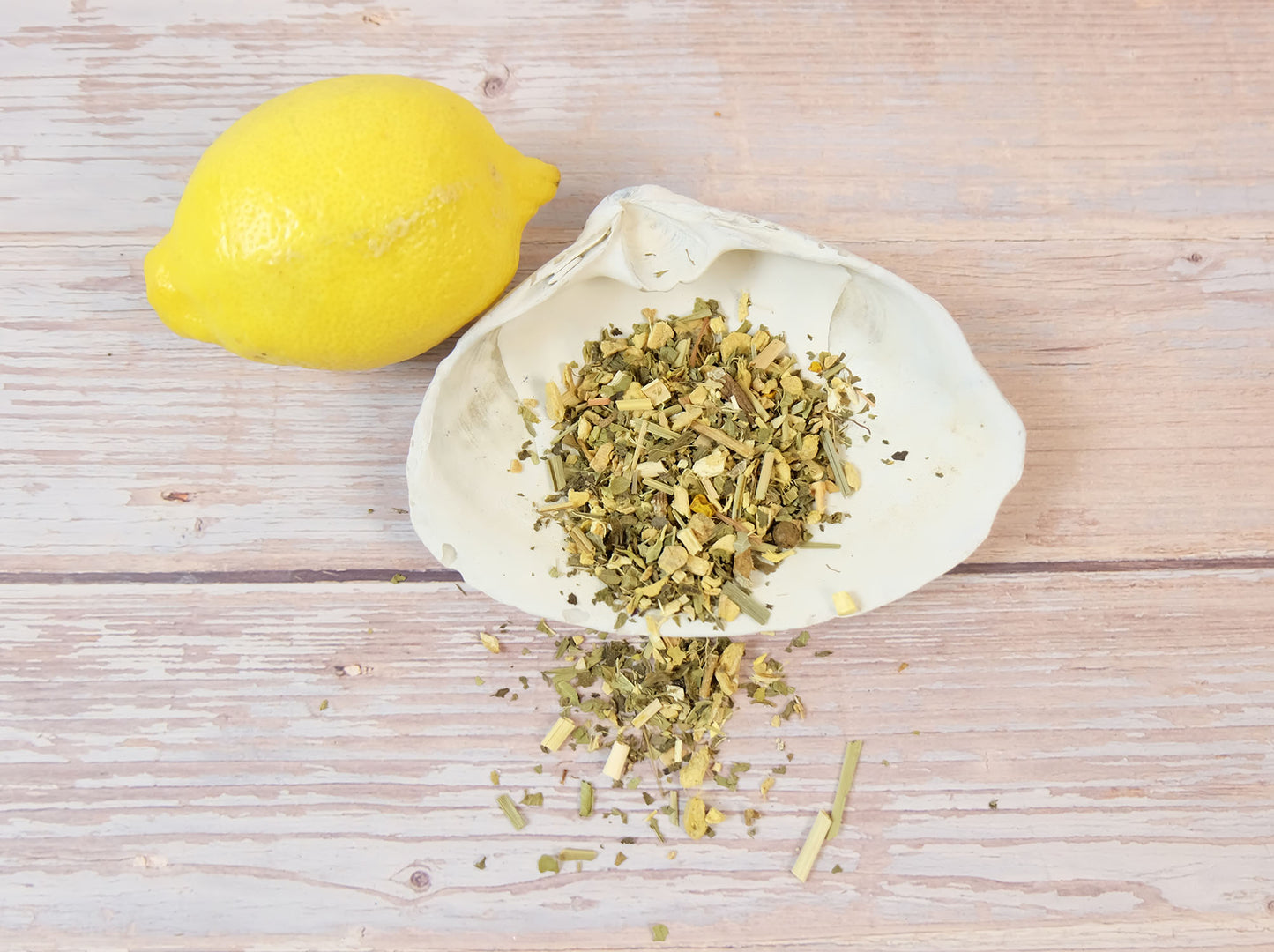 Lemon Ginger Tea loose leaf tea in a white shell with a lemon wedge beside it