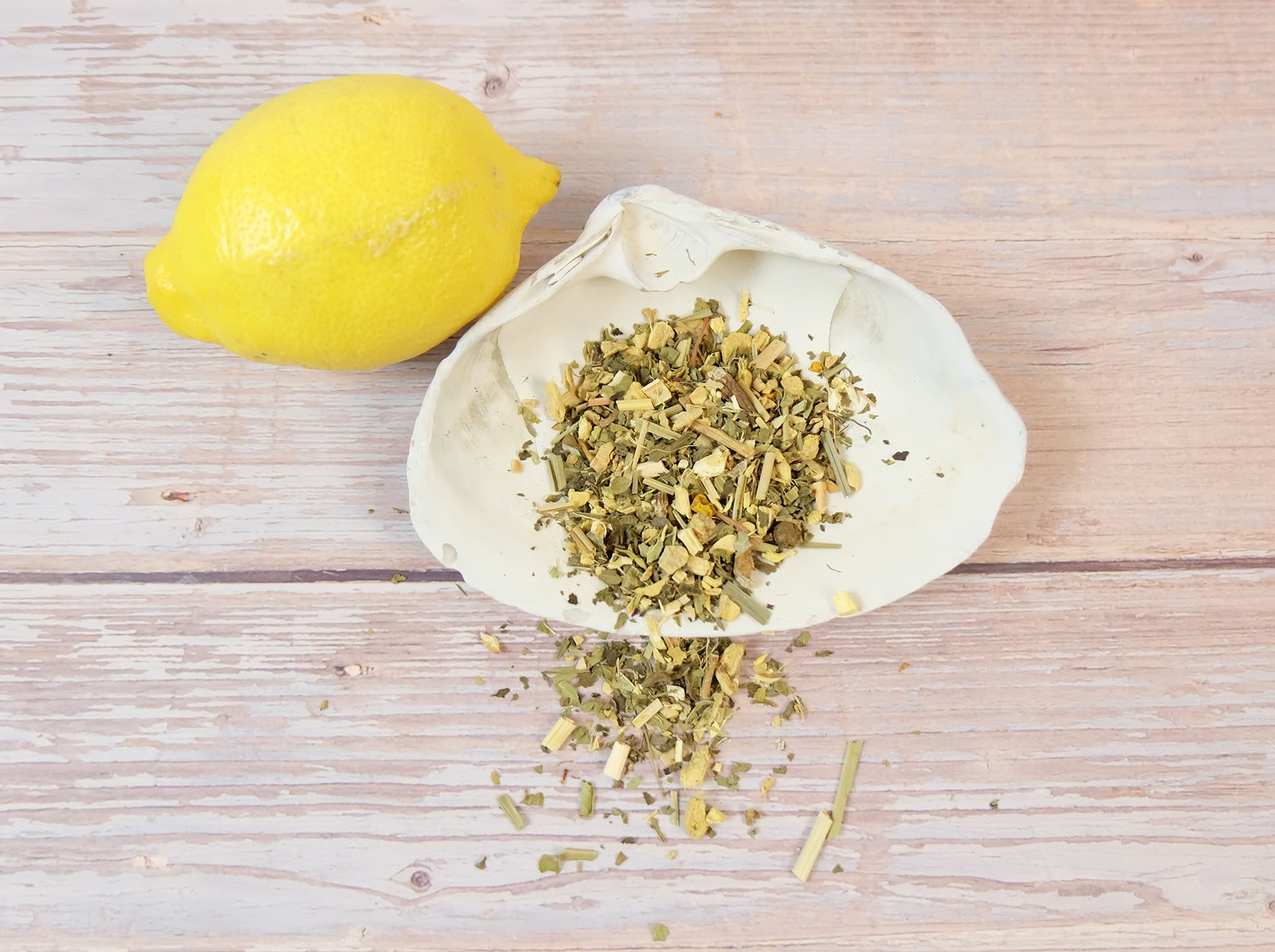 Lemon Ginger Tea loose leaf tea in a white shell with a lemon wedge beside it