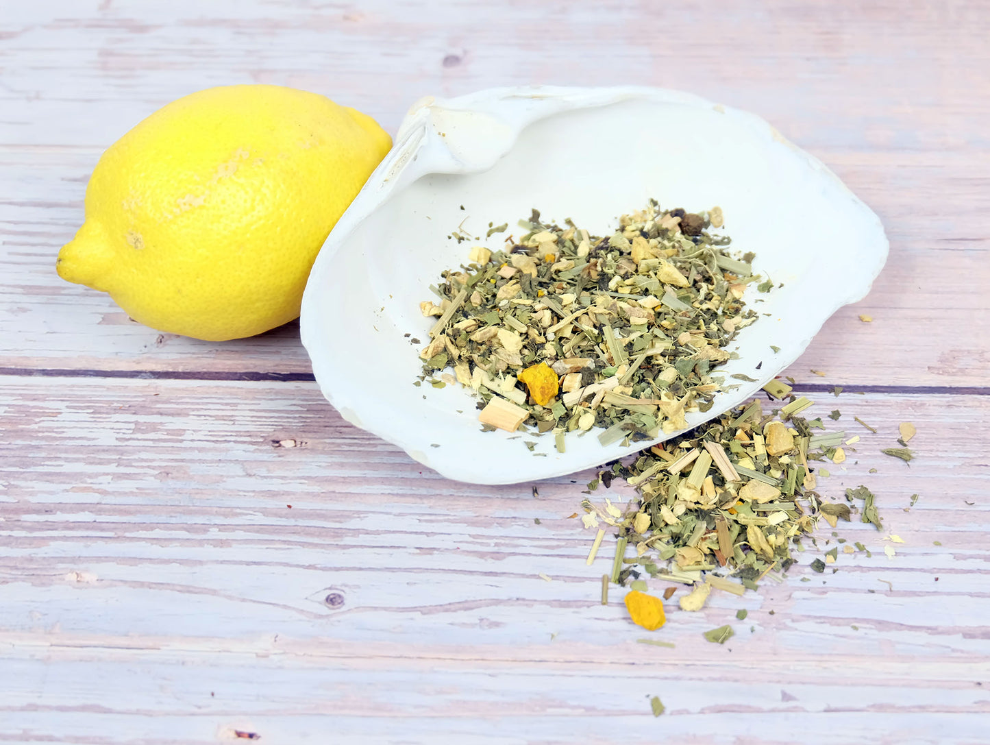 Lemon Ginger Tea loose leaf tea spilling from a shell with a lemon beside it