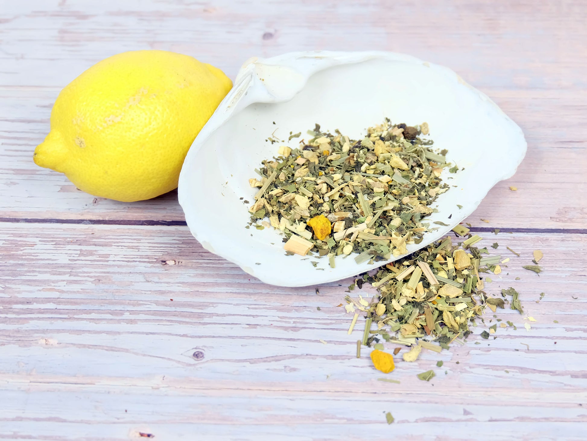Lemon Ginger Tea loose leaf tea spilling from a shell with a lemon beside it