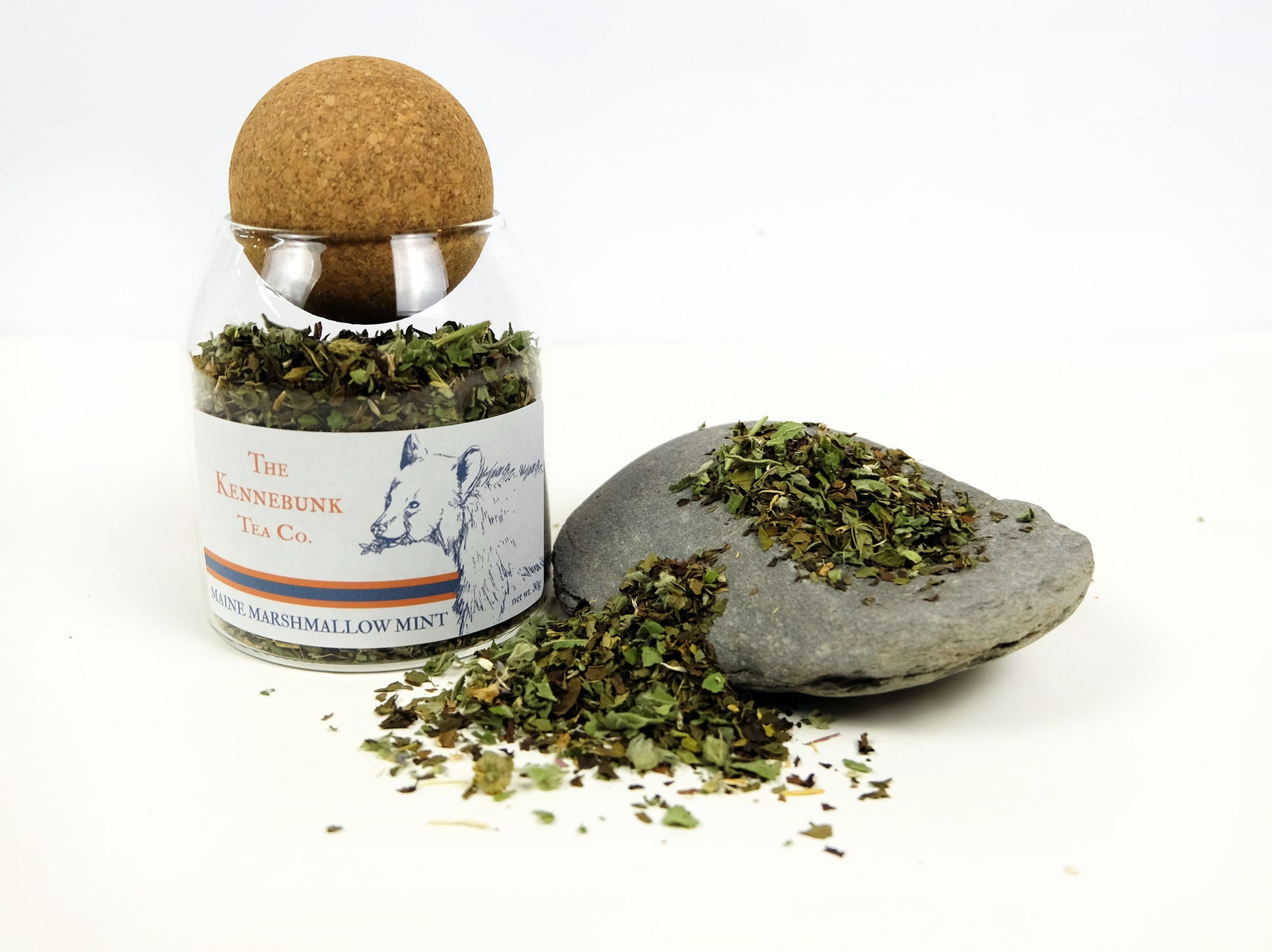 Marshmallow Mint Tea loose leaf tea on a rock next to a glass jar of tea