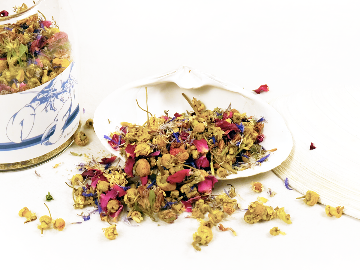 New England Garden Tea loose leaf tea on a white shell with part of a glass jar visible, close-up