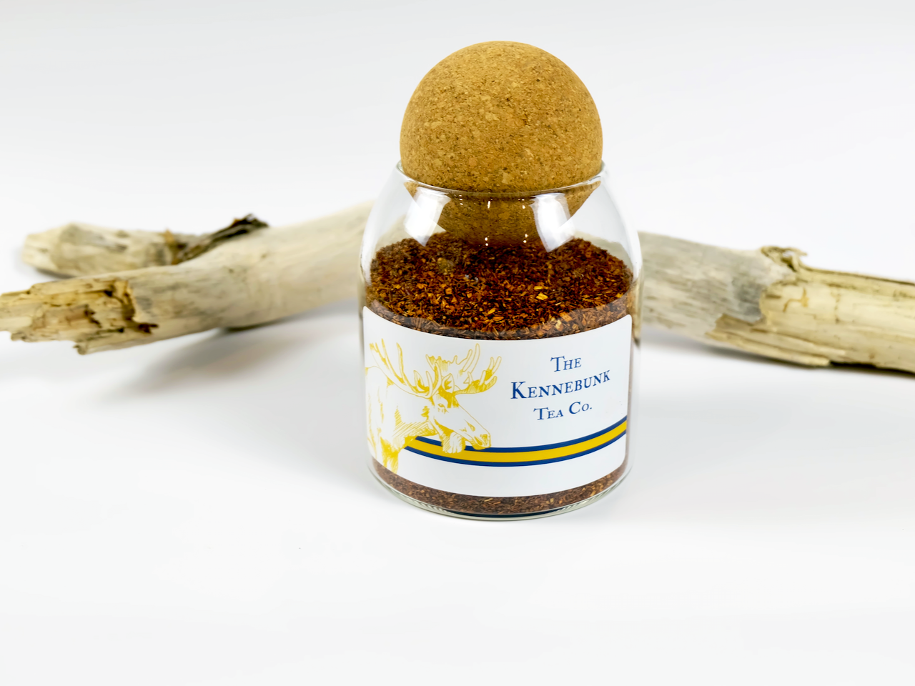 Organic Rooibos loose leaf tea in a glass jar with driftwood beside it