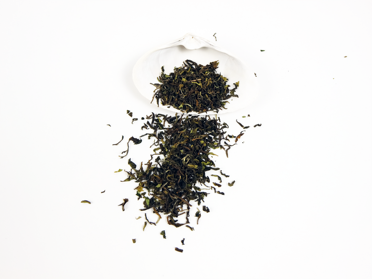 Orange Valley first flush Darjeeling loose leaf tea in a white shell, leaves spilling over the side