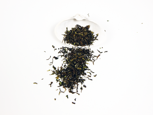 Orange Valley first flush Darjeeling loose leaf tea in a white shell, leaves spilling over the side