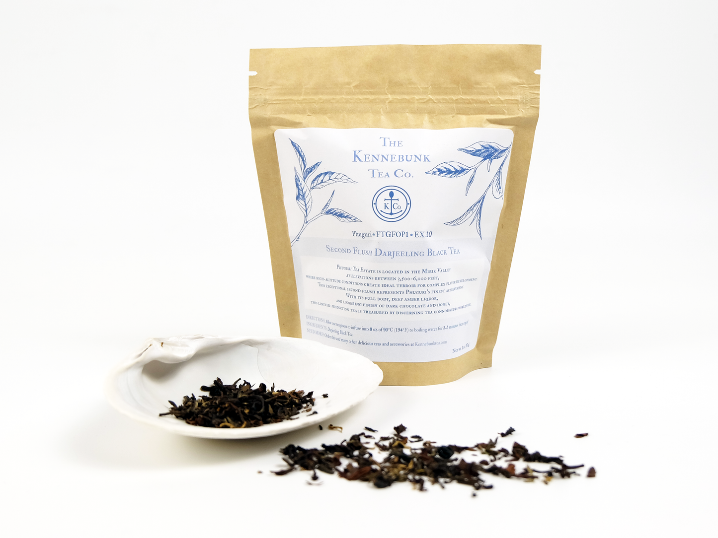 Phuguri second flush Darjeeling loose leaf tea on a white shell with a 4oz kraft tea bag behind